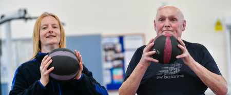 Two adults holding basketballs inside a gym
