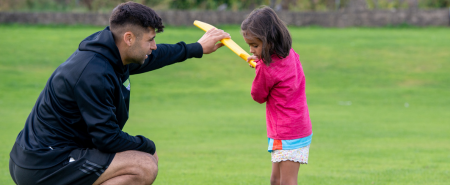 A man coaching a young in cricket